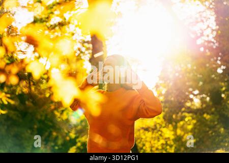 Donna che indossa le cuffie che ama le passeggiate autunnali nella natura Foto Stock