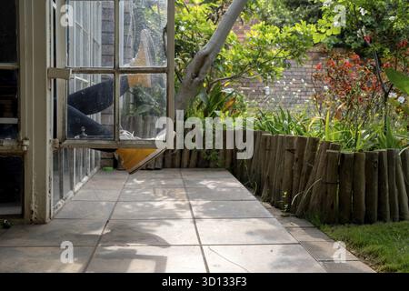 Gambe sporgenti da una finestra, vista giardino Foto Stock