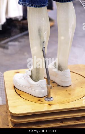 Casablanca, Casablanca-Settat - Marocco - 07-27-2024: Gambe manichini con scarpe da ginnastica bianche, esposte su una piattaforma di legno Foto Stock