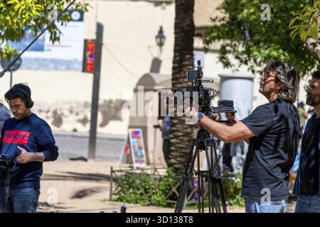 Cordoba, Cordoba - Spagna - 04-08-2024: Un cameraman che regola le attrezzature professionali durante una produzione all'aperto a Cordoba Foto Stock