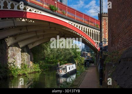 Un canale in barca stretta che passa sotto un ponte ferroviario ad arco vittoriano, sul canale di Rochdale, Castlefield, Manchester, Regno Unito Foto Stock