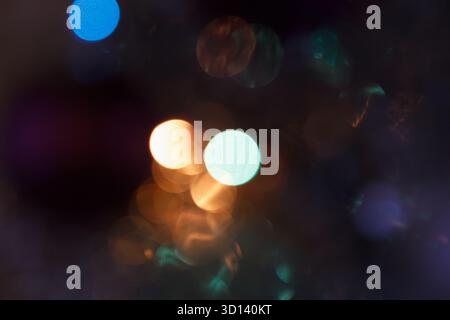 Luci bokeh astratte in vari colori, creando uno sfondo morbido e sognante. La scenografia presenta forme circolari sfocate nelle tonalità blu, arancione e verde Foto Stock