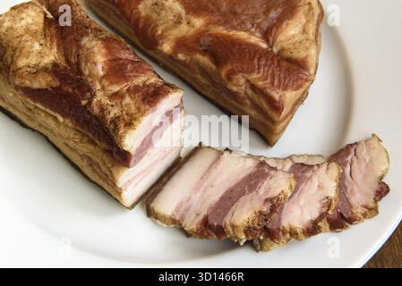 Costolette di maiale affumicate su piatto bianco su fondo in legno Foto Stock