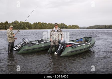 Due pescatori sul fiume con barche a motore Foto Stock