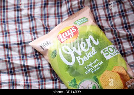 KIEV, UCRAINA - 19 APRILE 2025 giace lo yogurt al forno con patatine aromatizzate all'erba in una confezione verde con il logo ufficiale Foto Stock