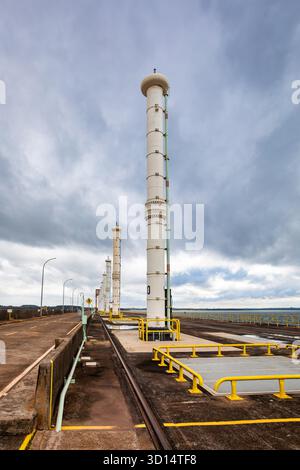 Itaipu Binacional, Brasile - 22 giugno 2025: Una serie di colonne torreggianti segna la struttura di aspirazione in cima all'immensa diga idroelettrica di Itaipu. Foto Stock