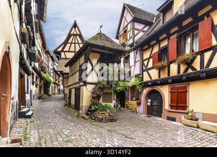 Eguisheim, Francia - 8 luglio 2019: Case colorate in legno dell'alsaziano nel villaggio di Eguisheim, Francia Foto Stock