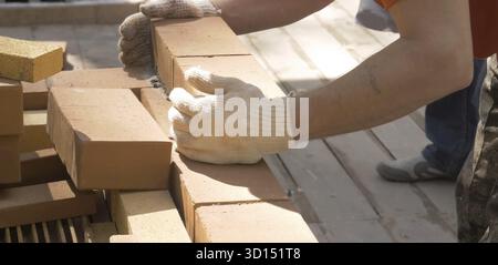 Un uomo costruisce un muro di mattoni. Brick ha messo la soluzione. Costruzione di una casa in mattoni Foto Stock