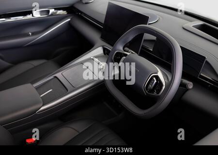 Primo piano di un abitacolo moderno e lussuoso incentrato sul volante e sul cruscotto. Concetto di tecnologia dei veicoli, design premium e settore automobilistico Foto Stock