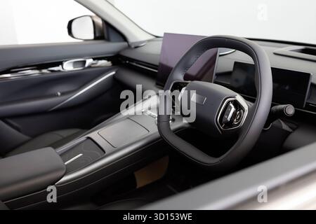 Primo piano di un abitacolo moderno e lussuoso incentrato sul volante e sul cruscotto. Concetto di tecnologia dei veicoli, design premium e settore automobilistico Foto Stock