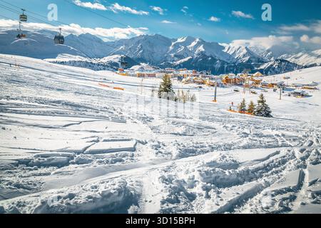 Splendida pista da sci con piste da sci nella neve fresca e profonda. Stazione sciistica invernale con splendidi edifici alpini e funivie, Alpe d'Huez, Francia, Euro Foto Stock