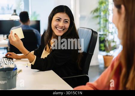 Due diverse collaboratrici che parlano mentre lavorano in un ufficio moderno Foto Stock