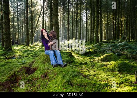 Una giovane donna con il suo cane da compagnia nel bosco in Cornovaglia, Regno Unito Foto Stock