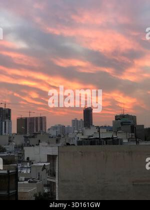 Cielo colorato al tramonto sullo skyline della città di Teheran, Iran, con edifici e gru moderni. Foto Stock