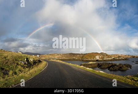 Un arcobaleno sulla strada costiera vicino al punto panoramico delle foche sull'Isola di Harris, Ebridi esterne, Scozia, con cieli molli e aspri paesaggi dell'isola. Foto Stock