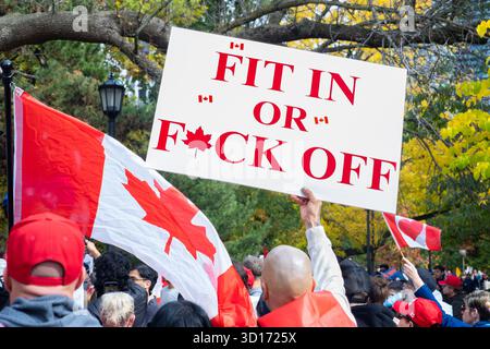 Un cartello con scritto 'Fit in or F*ck Off' ad un rally Canada First nel Queen's Park a Toronto, Ontario, il 25 ottobre 2025 Foto Stock