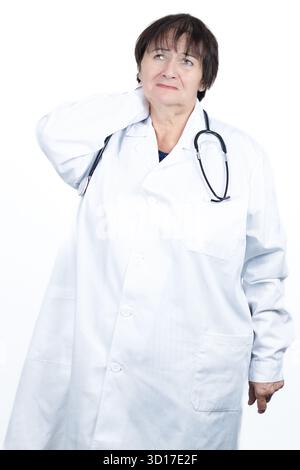 Medico donna matura stressata in un camice da laboratorio e uno stetoscopio che tiene il collo dolorante, riflettendo il fisico Foto Stock