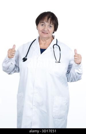 Donna anziana che indossa un camice da laboratorio bianco e uno stetoscopio sorridente, che dà due pollici in su, simboleggia l'approvazione, buone notizie Foto Stock