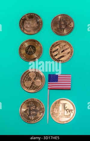 Monete di criptovaluta tra cui Bitcoin, Dogecoin, Litecoin e Ripple, accanto a una bandiera degli Stati Uniti su sfondo verde. Foto Stock