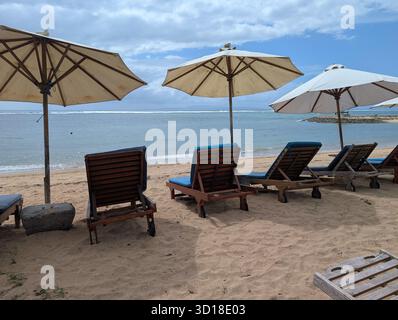 Sedie a sdraio con ombrelloni a Sanur Beach, Bali, Indonesia Foto Stock