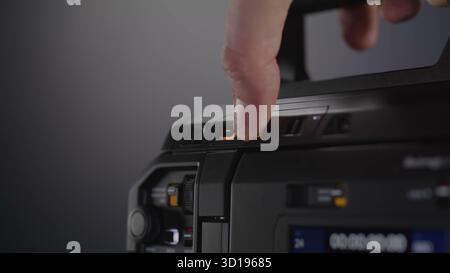 Un dito inserisce il pulsante di registrazione illuminato su un professionista. Foto Stock