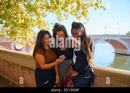 Diverse donne e amici che condividono contenuti su smartphone a tolosa Foto Stock