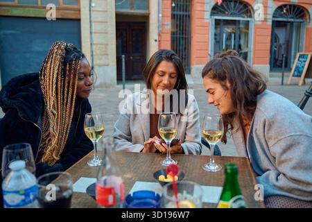 Donne e amici che amano il vino e condividono i contenuti dello smartphone all'aperto Foto Stock