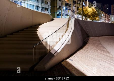 Scala illuminata e parete sinuosa in cemento Foto Stock