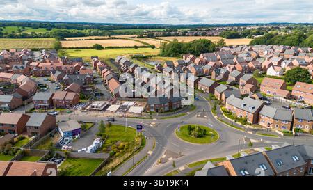 Foto aerea del villaggio di Cotchett, Mickleover, Derby, che mostra la tenuta residenziale e la rotatoria vicino alla campagna aperta. Foto Stock