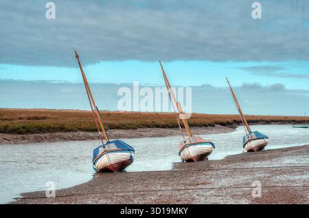 Tre in fila, yacht sui pianali fangosi, Blakeney North Norfolk, Regno Unito Foto Stock