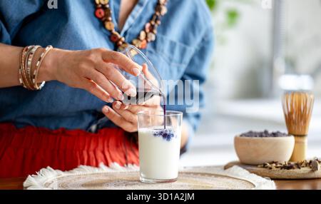 La donna versa Un Matcha latte con ghiaccio e latte in Un barattolo Foto Stock