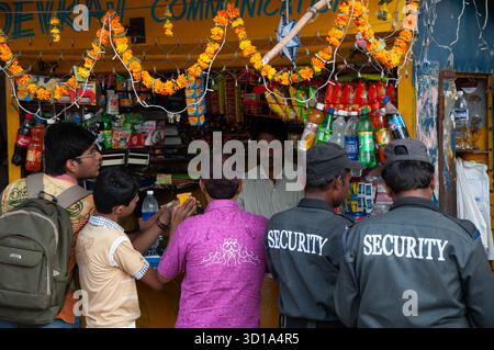 Mumbai, India - 17 ottobre 2009: Vista di un vivace negozio sul lato della strada adornato di ghirlande, mentre i clienti si riuniscono e il personale di sicurezza guarda, creando un ambiente urbano dinamico. Foto Stock