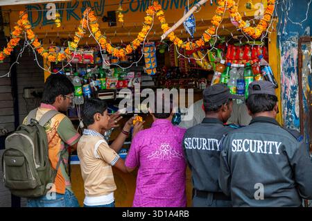 Mumbai, India - 17 ottobre 2009: Vista di un vivace negozio sul lato della strada adornato da vivaci ghirlande, dove la gente del posto e il personale di sicurezza si riuniscono, colori che spuntano contro la facciata intemprata. Foto Stock