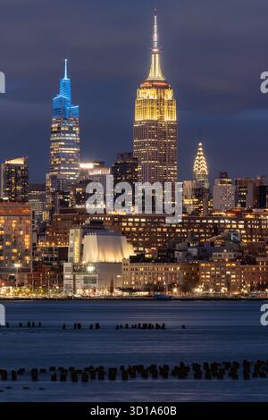 Vista notturna di New York dal fiume Hudson di Midtown Manhattan con i grattacieli illuminati dell'Empire State Building, un Vanderbilt e il Chrysler Building Foto Stock