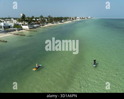 La vista aerea delle acque turchesi incontra le sabbie pallide della costa, dove i pagaiatori scorrono davanti a moderne ville bianche sotto il vasto cielo blu, Progreso, Yucatan, Messico. Foto Stock