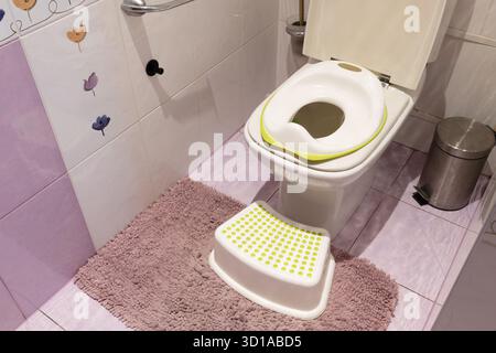 WC per bambini in cima al grande WC e gradino in plastica sul tappeto in bagno Foto Stock