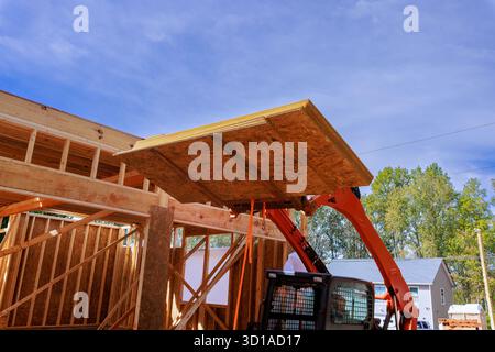 I macchinari pesanti sollevano grandi pannelli in legno OSB in cantiere Foto Stock