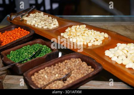 Tagliere di salumi con cubetti di formaggio, arachidi, piselli e cereali assortiti, perfetto per la festa, antipasto o riunione sociale Foto Stock
