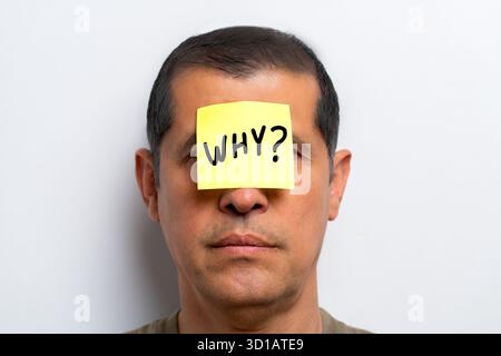 Domanda esistenziale. Perché è scritto a mano su una nota adesiva e attaccato alla fronte di un uomo? Un concetto filosofico sullo scopo della vita. Foto Stock