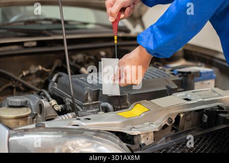 Primo piano di un meccanico che controlla il livello dell'olio in un meccanico dell'officina Foto Stock