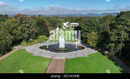 Vista aerea del parco pubblico con grande fontana. Il drone cattura un paesaggio panoramico di un verde parco cittadino con una grande fontana e sentieri per passeggiate Foto Stock