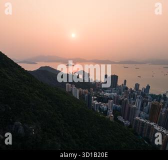 Vista del tramonto sul mare e dello skyline della città con edifici sul lato della montagna, Hong Kong, Hong Kong Island, Hong Kong. Foto Stock