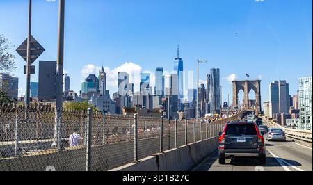 Attraversa il ponte di Brooklyn fino a Manhattan, New York City, con il centro di Manhattan e il One World Trade visibile oltre la torre del ponte, POV dall'auto Foto Stock
