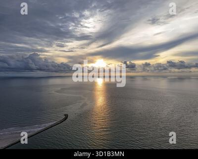Vista aerea dei raggi dorati del sole che si riflettono sul mare tranquillo, proiettando un caldo bagliore sull'orizzonte durante il tramonto, Clearwater, Florida, Unit Foto Stock