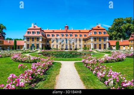 Vista panoramica del castello di Rajec Jestrebi in una soleggiata giornata estiva con cielo blu, rose rosa fiorenti e una fontana di fronte all'edificio storico. Foto Stock
