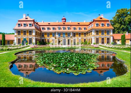 Vista panoramica del castello di Rajec Jestrebi in una soleggiata giornata estiva con cielo blu, rose rosa fiorenti e una fontana di fronte all'edificio storico. Foto Stock