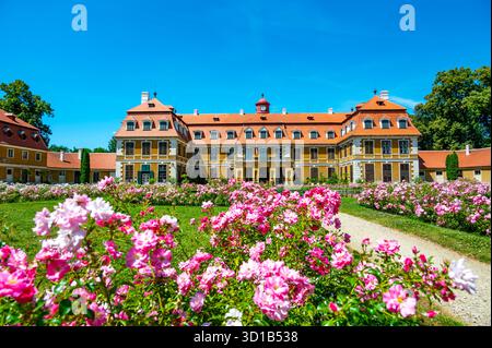 Vista panoramica del castello di Rajec Jestrebi in una soleggiata giornata estiva con cielo blu, rose rosa fiorenti e una fontana di fronte all'edificio storico. Foto Stock