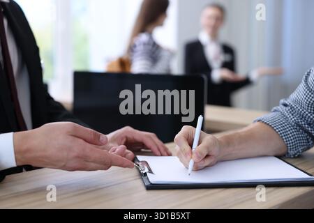 L'addetto alla reception lavora con gli ospiti al banco della reception dell'hotel, primo piano Foto Stock