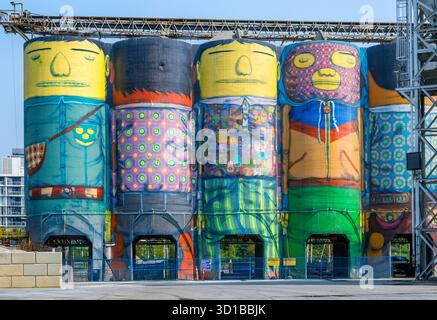 Murale «Giants» dipinto su silos di cemento a Granville Island, Vancouver, British Columbia, Canada. L'opera è dell'artista brasiliano Osgemeos. Foto Stock