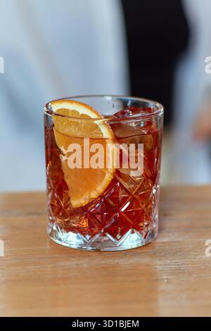 Il barman spreme a mano il succo fresco di lime nel bicchiere per preparare il cocktail Caipirinha al bancone del bar. Foto Stock